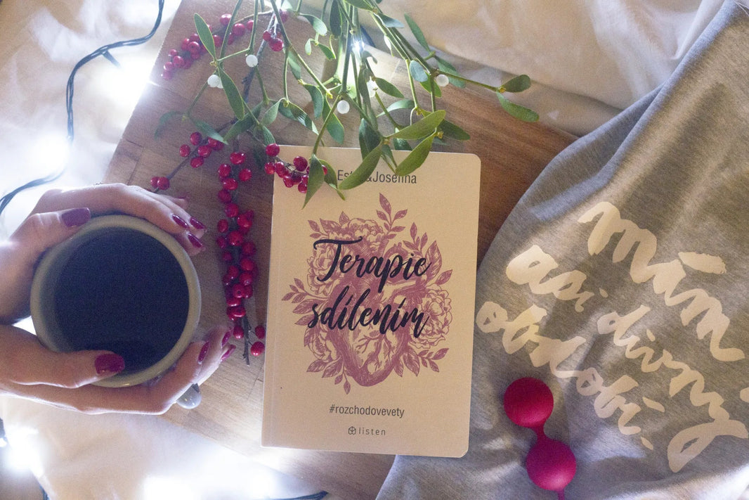 Whoop-de-doo red silicone Kegel balls placed next to a book and a cup of coffee on a wooden tray.