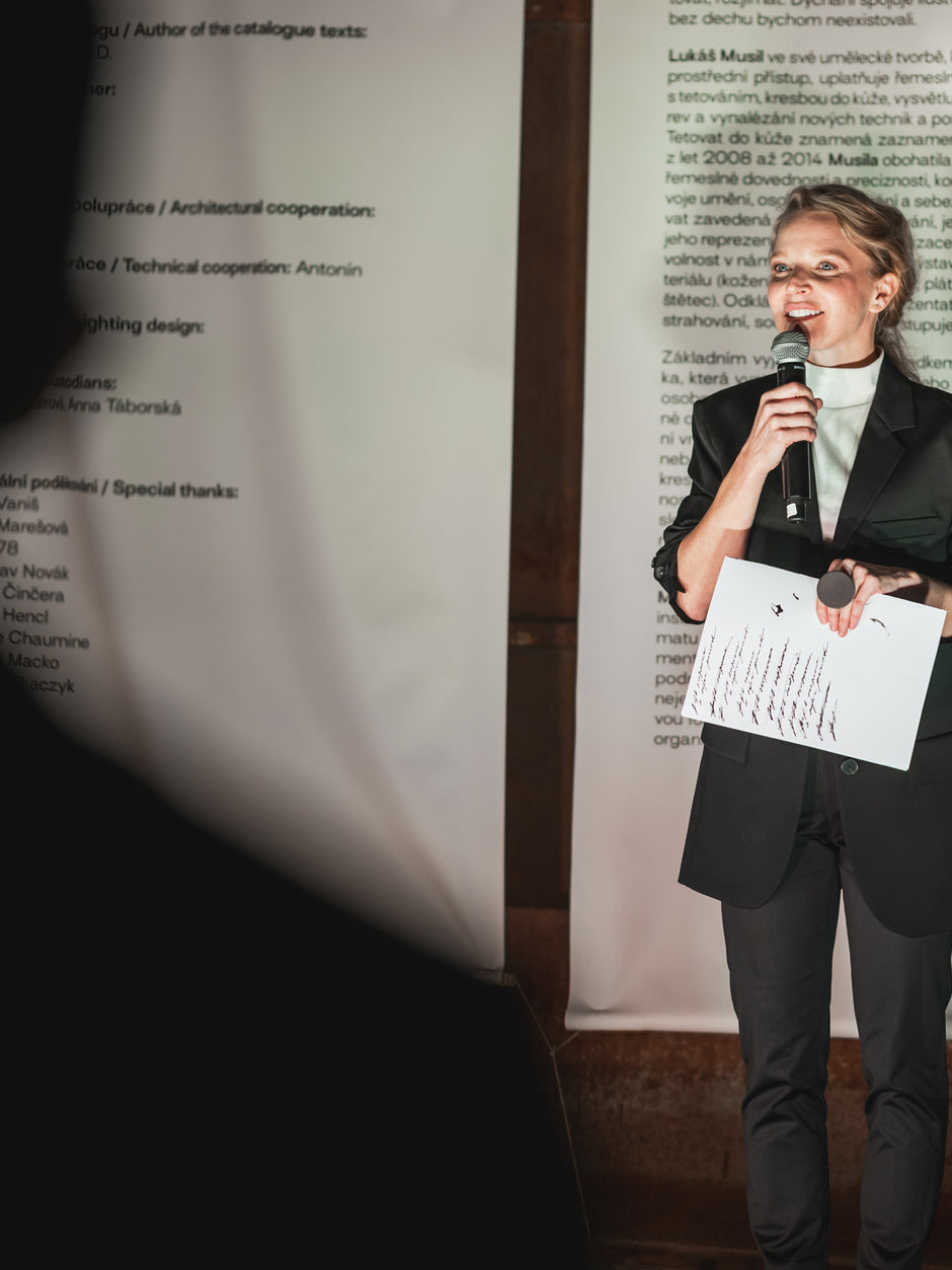 Whoop-de-doo founder Anna Marešová holding a microphone and speaking at a brand event.