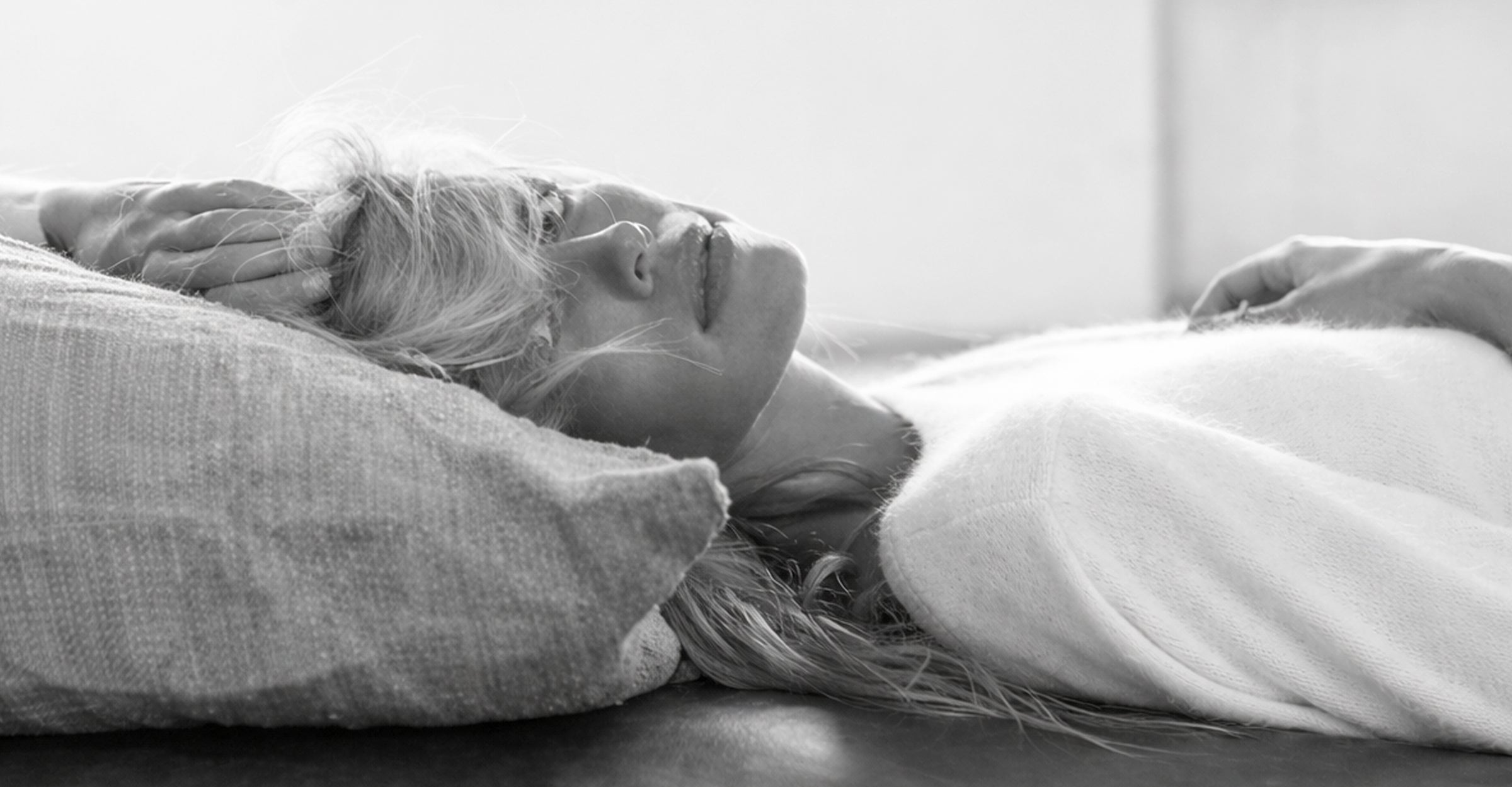Close-up black and white photograph of a woman lying on a pillow capturing a moment of bliss and relaxation.