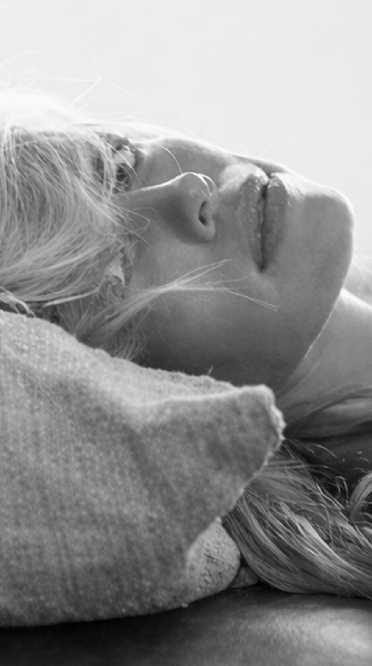 Close-up black and white photograph of a woman’s face on a pillow capturing a moment of bliss and relaxation.