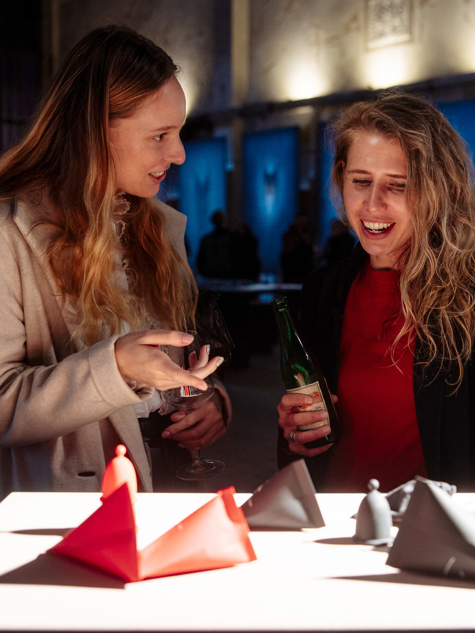 Two smiling women talking over a showroom display featuring colorful Whoop-de-doo menstrual cups.