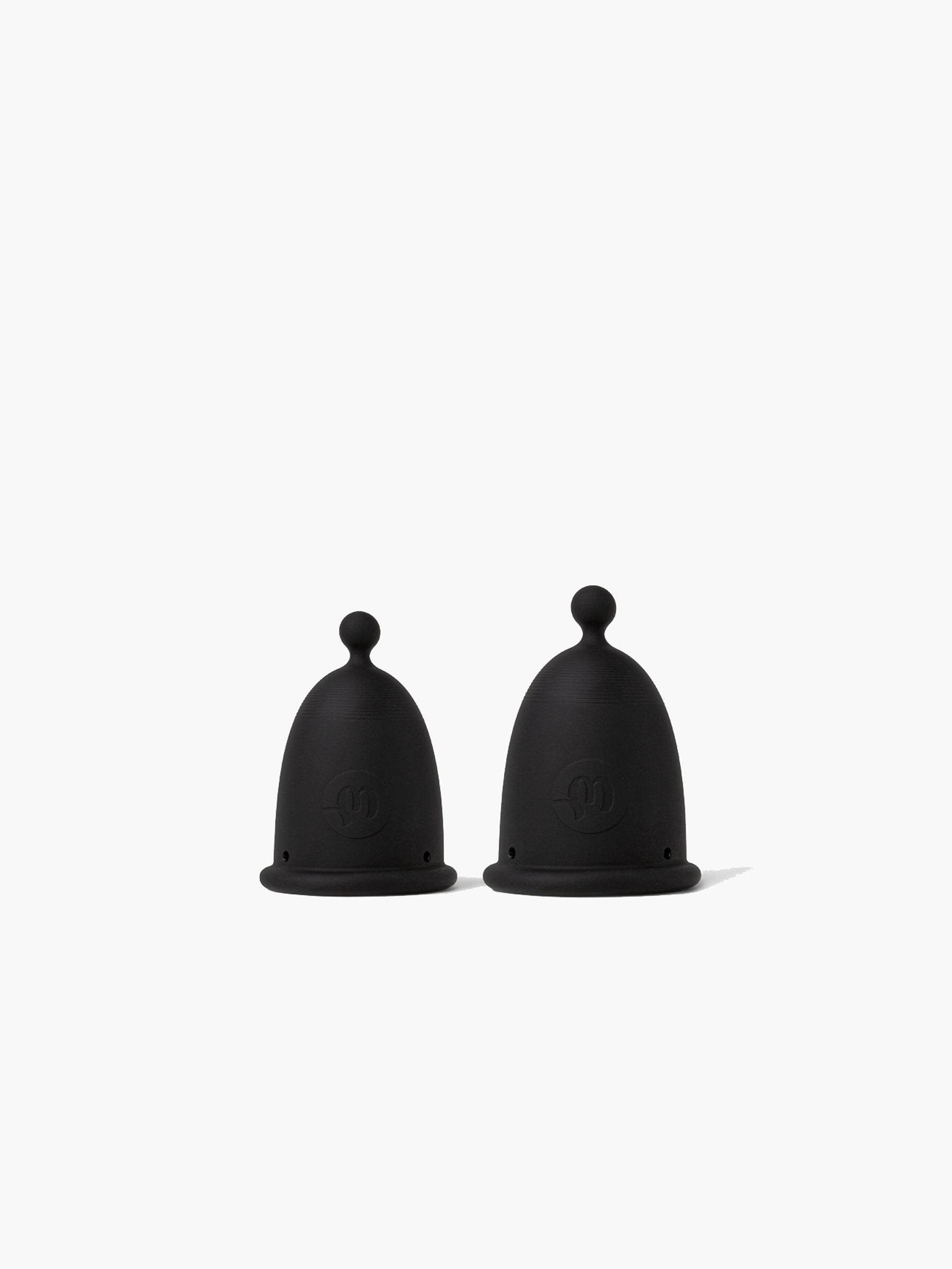 Two black-grey Whoop-de-doo menstrual cups from the Duo pack standing side by side, featuring both sizes for flexible period protection.