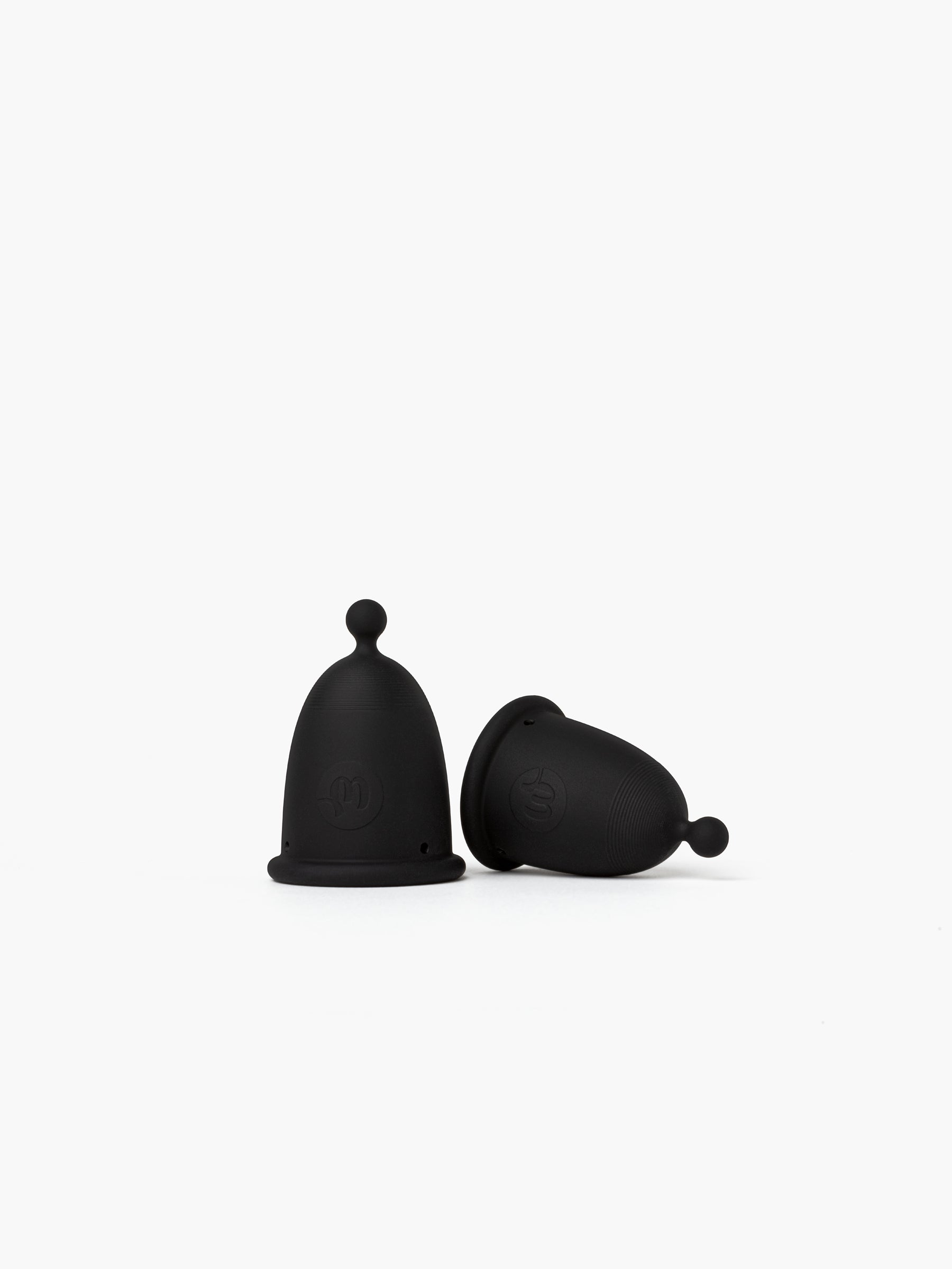 Black-grey Whoop-de-doo menstrual cups from the Duo pack displayed on a white background – one standing and one lying on its side, showcasing the velvety matte texture of the medical-grade silicone.