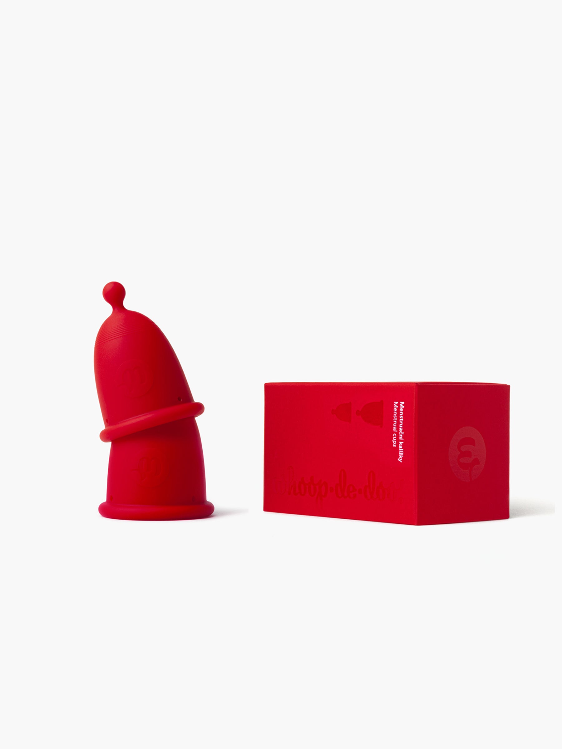 Red and black-grey Whoop-de-doo menstrual cups from the Duo pack stacked on top of each other next to their elegant red gift packaging box.
