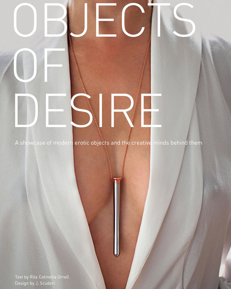 Cover of the international book Objects of Desire, showcasing a woman in a white blazer wearing a metallic vibrator necklace, celebrating modern erotic design.