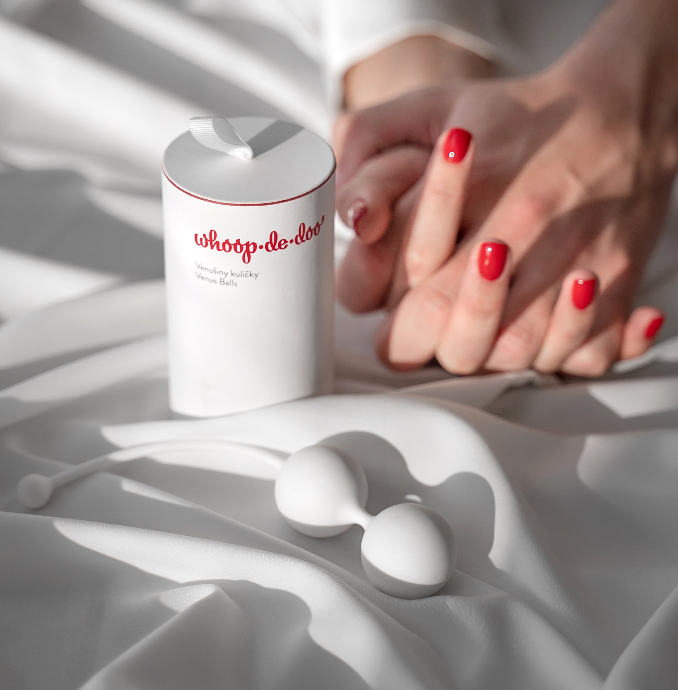 Close-up of the medical-grade silicone Whoop-de-doo pelvic floor exercise beads with their elegant white and red product packaging box.