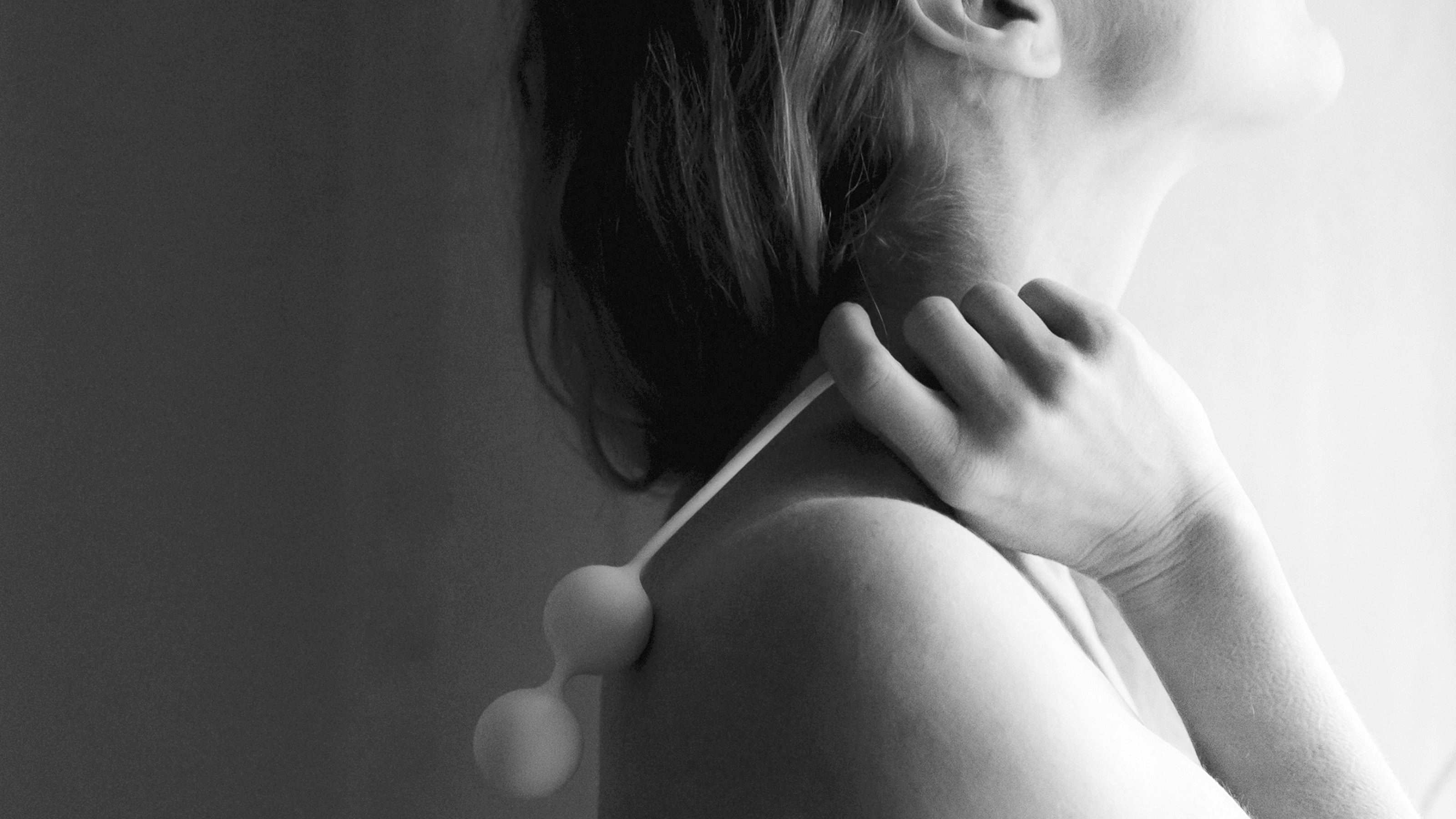 Black and white photo of a woman's bare back with white Whoop-de-doo Venus balls over her shoulder.